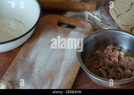Der Prozess der Herstellung von hausgemachten Knödel in der Küche. Hackfleisch, Teig, Mehl und Küchenutensilien auf dem Tisch. Köstliche traditionelle hausgemachte f Stockfoto