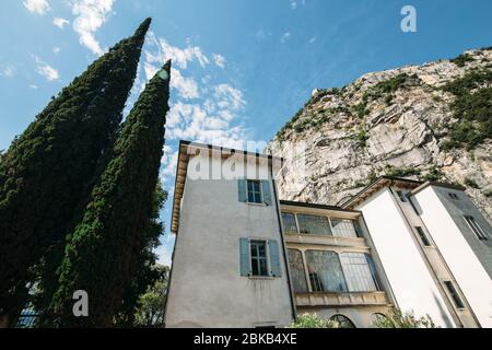 Altes Haus unter dem Berg neben Zypressen auf einem Hintergrund des blauen Himmels in Italien Stockfoto