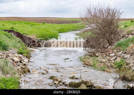 Wasser, das nach starkem Regen und Stürmen in der Farm Field Waterway floss, verursachte Überschwemmungen. Konzept der Bodenerosion, Kontrolle und Bewirtschaftung der Wasserabflüsse Stockfoto