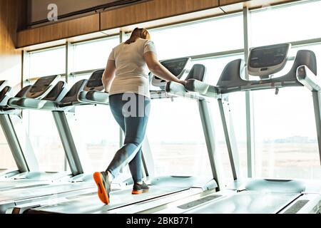 Übergewicht Mädchen, die auf dem Laufband im Fitnessstudio gegen Fenster Stockfoto