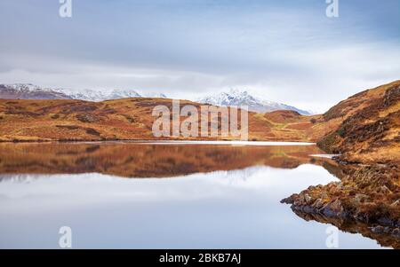 Beacon Tarn in den Blawith Fells mit dem schneebedeckten 'Old man of Coniston' in der Ferne, Lake District, England Stockfoto