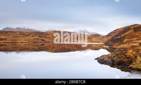 Beacon Tarn in den Blawith Fells mit dem schneebedeckten 'Old man of Coniston' in der Ferne, Lake District, England Stockfoto