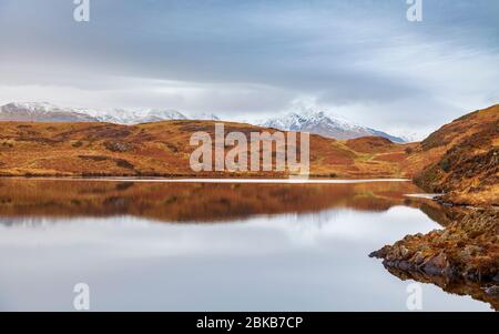 Beacon Tarn in den Blawith Fells mit dem schneebedeckten 'Old man of Coniston' in der Ferne, Lake District, England Stockfoto