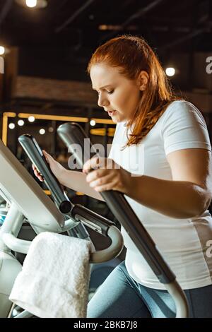 Konzentrierte übergewichtige Mädchen Training auf Schritt-Maschine im Fitnessstudio Stockfoto