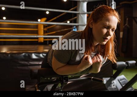 Übergewichtige Mädchen mit geschlossenen Augen tun unteren Rücken Verlängerung Übung auf Trainingsgerät Stockfoto