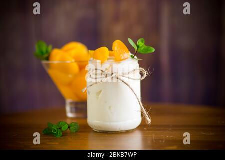 Hausgemachter süßer Joghurt mit Scheiben eingelegter Pfirsiche in einem Glasgefäß Stockfoto