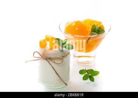 Hausgemachter süßer Joghurt mit Scheiben eingelegter Pfirsiche in einem Glasgefäß Stockfoto
