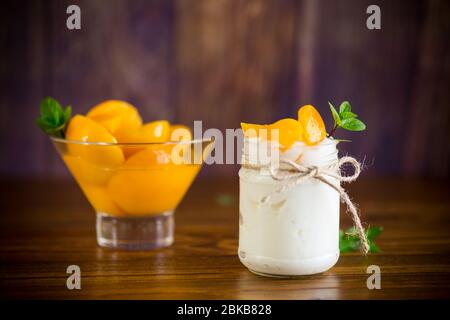 Hausgemachter süßer Joghurt mit Scheiben eingelegter Pfirsiche in einem Glasgefäß Stockfoto