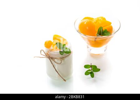 Hausgemachter süßer Joghurt mit Scheiben eingelegter Pfirsiche in einem Glasgefäß Stockfoto