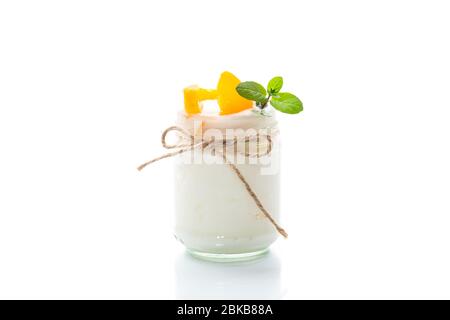 Hausgemachter süßer Joghurt mit Scheiben eingelegter Pfirsiche in einem Glasgefäß Stockfoto