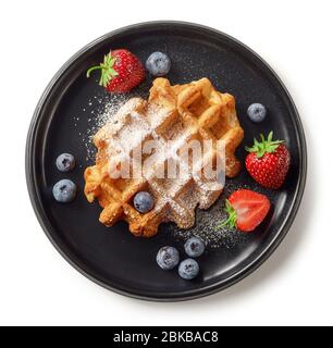 Frisch gebackene belgische Waffel auf schwarzem Teller isoliert auf weißem Hintergrund, Draufsicht Stockfoto