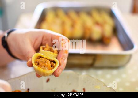 Zubereitung von hausgemachten Lumaconi gefüllt mit Tomatensauce und Hackfleisch. Nahaufnahme von Menschenhänden Füllung hausgemachte italienische Pasta Rezept. Stockfoto