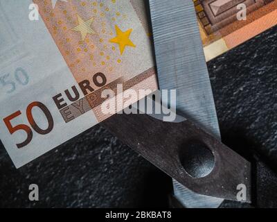 Reduzierung von Emissionen und Schulden zur Vermeidung von Wertverlust. Euro-Geldwährung in einer Schere platziert Stockfoto