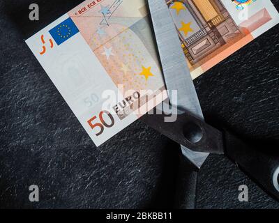 Reduzierung von Emissionen und Schulden zur Vermeidung von Wertverlust. Euro-Geldwährung in einer Schere platziert Stockfoto