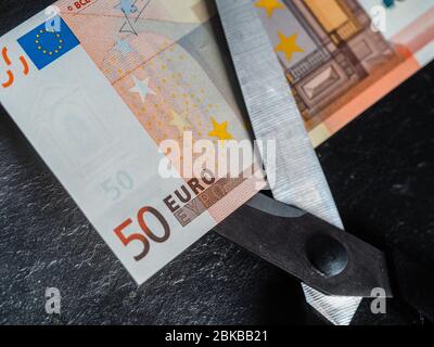 Reduzierung von Emissionen und Schulden zur Vermeidung von Wertverlust. Euro-Geldwährung in einer Schere platziert Stockfoto