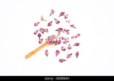 Rosenblüten. Trockene rosa Rosenknospen für Tee auf weißem Hintergrund. Seitenanfang gesunde Rosenknospen auf Holzlöffeln, isoliert. Stockfoto
