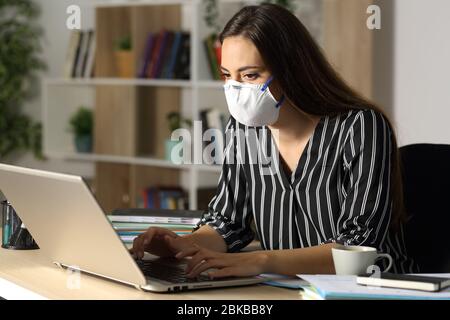 Serious Unternehmer arbeiten auf Laptop Vermeidung covid-19 Ansteckung mit Schutzmaske sitzen zu Hause im Büro in der Nacht Stockfoto