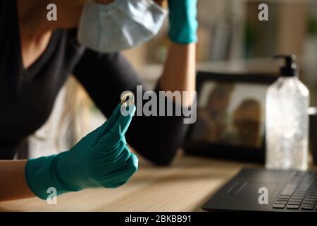 Nahaufnahme der traurigen Frau, die Ehering nach der Scheidung auf Coronavirus Confinement hält, auf einem Schreibtisch zu Hause in der Nacht sitzt Stockfoto