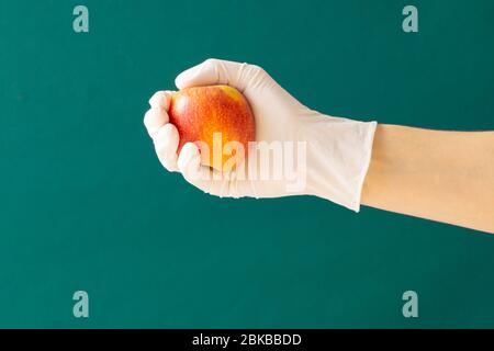 Gummi Handschuher hält einen Apfel. Konzept: Coronavirus. Kopierbereich. Stockfoto