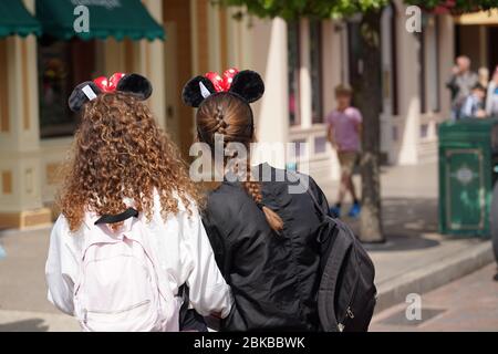 Hinterkopf von zwei jungen Mädchen. Aufenthalt auf der Straße mit Blick auf eine Attraktion im touristischen Park mit anderen Besuchern. Paris Frankreich, 29. Mai 2019 Stockfoto