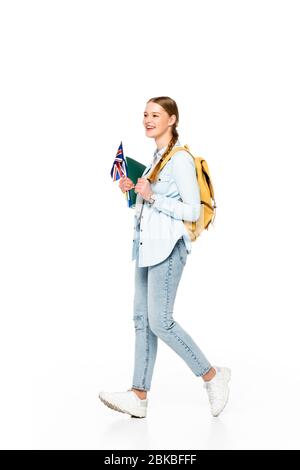 Lächelndes Mädchen mit Zopf und Rucksack, das mit Flagge von großbritannien und Copybooks auf weiß isoliert geht Stockfoto