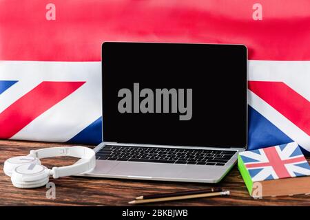 Laptop in der Nähe Buch mit uk Flagge und Kopfhörer auf Holztisch Stockfoto
