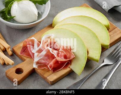 Melone und Schinken in Scheiben geschnitten auf Holzbrett Stockfoto