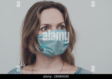 Porträt einer Frau, die eine medizinische Maske trägt und die Kamera betrachtet, isoliert. Grippeepidemie, Stauballergie, Virenschutz. Covid-19, Coronavirus pand Stockfoto