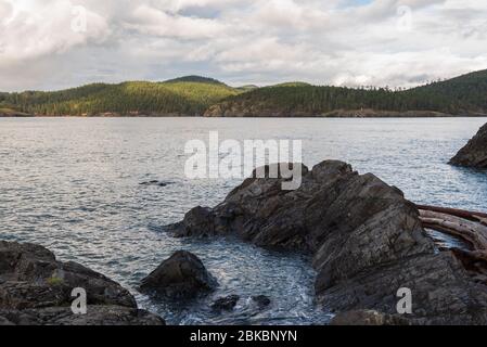 Landschaft aus Felsen, Meer und entfernten Hügeln im Deception Pass State Park in Washington Stockfoto