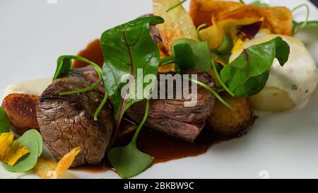 Gegrilltes mittelseltenes Rindfleisch Steak mit gebackenen Kartoffeln, grünen Blättern Salat Stockfoto
