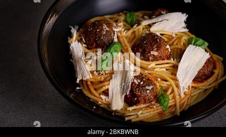 Spaghetti Pasta mit Fleischbällchen in einer schwarzen Schüssel. Kopierraum. Stockfoto