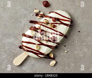 Vanilleeis mit geschmolzener Schokolade und Haselnüssen dekoriert, Draufsicht Stockfoto