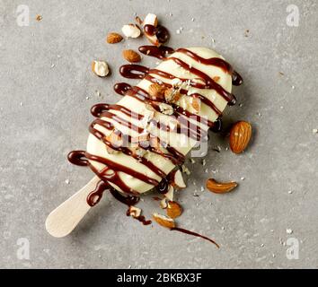 Eis mit weißer Schokolade bedeckt mit Schokolade und Mandeln auf grauem Teller Hintergrund dekoriert, Draufsicht Stockfoto