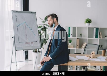 Verärgert Geschäftsmann mit Kreditkarten, während in der Nähe Flipchart mit Grafiken, die Rezession Stockfoto