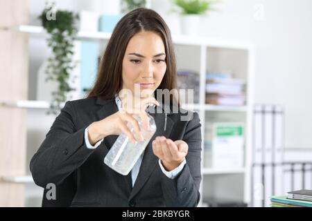 Seriöse leitende Frau, die im Büro den Flaschenspender mit Handdesinfektionsmittel drückt Stockfoto