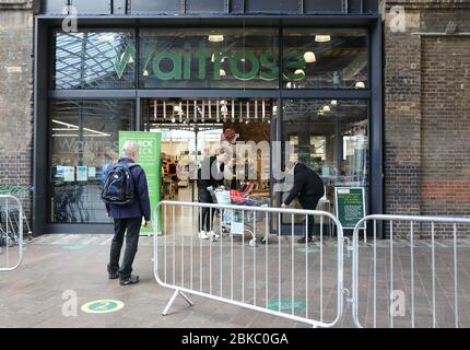 Kunden ermutigen, die Quick Check-App für den schnellen Einkauf bei Waitrose in der Sperrung der Coronavirus-Pandemie, Kings Cross, Großbritannien, zu verwenden Stockfoto