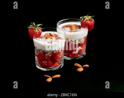 Frische Erdbeeren mit Sojoghurt, Haferflocken, Mandeln, roter Fruchtmarmelade, Kokosmehl und Chiasamen. Stockfoto