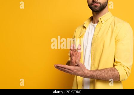 Zugeschnittene Ansicht des Mannes, der Geste in tauber und stummer Sprache auf gelbem Hintergrund zeigt Stockfoto