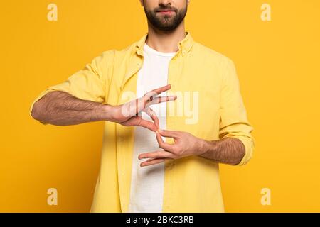 Zugeschnittene Ansicht des Mannes, der Deutungszeichen in tauber und stummer Sprache auf gelbem Hintergrund zeigt Stockfoto
