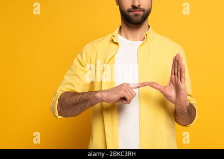 Zugeschnittene Ansicht des Mannes, der Geste von Gebärdensprache auf gelbem Hintergrund zeigt Stockfoto