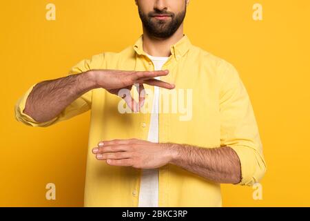 Beschnittene Ansicht des Menschen während der Verwendung Gebärdensprache auf gelbem Hintergrund gestikuliert Stockfoto