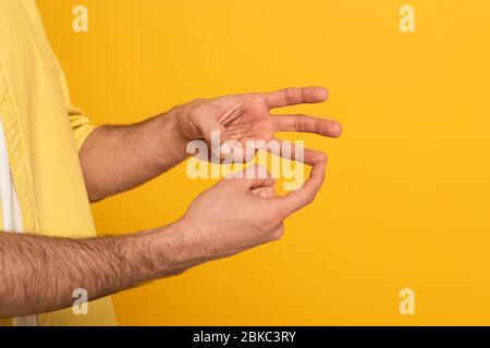 Zugeschnittene Ansicht des Mannes, der Geste in tauber und stummer Sprache auf Gelb isoliert zeigt Stockfoto
