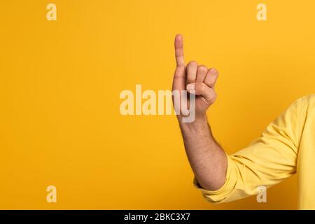 Zugeschnittene Ansicht des Mannes, der Brief in tauber und stummer Sprache auf gelbem Hintergrund zeigt Stockfoto