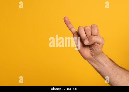 Zugeschnittene Ansicht des Mannes, der Brief in tauber und stummer Sprache auf gelb isoliert zeigt Stockfoto