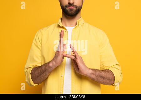 Zugeschnittene Ansicht des Mannes, der Schild in tauber und stummer Sprache auf gelbem Hintergrund zeigt Stockfoto