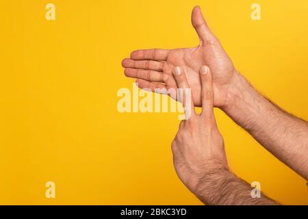 Zugeschnittene Ansicht des Mannes, der Geste in tauber und stummer Sprache auf Gelb isoliert zeigt Stockfoto