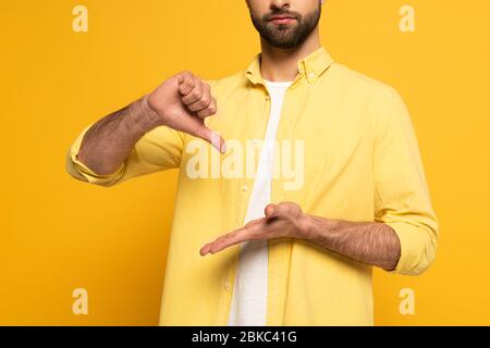 Zugeschnittene Ansicht des Mannes, der Schild in tauber und stummer Sprache auf gelbem Hintergrund zeigt Stockfoto