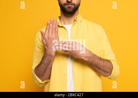 Zugeschnittene Ansicht des Mannes, der Geste von Gebärdensprache auf gelbem Hintergrund zeigt Stockfoto