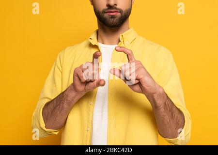 Zugeschnittene Ansicht des Mannes, der Schild in tauber und stummer Sprache auf gelbem Hintergrund zeigt Stockfoto