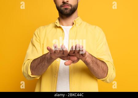 Zugeschnittene Ansicht des Mannes, der Geste in tauber und stummer Sprache auf gelbem Hintergrund zeigt Stockfoto